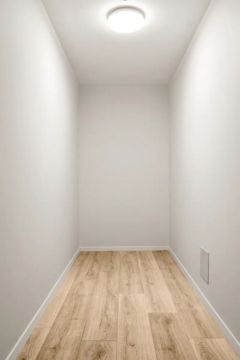 Rincón vacío de paredes blancas y piso de madera, antes de instalar el clóset.