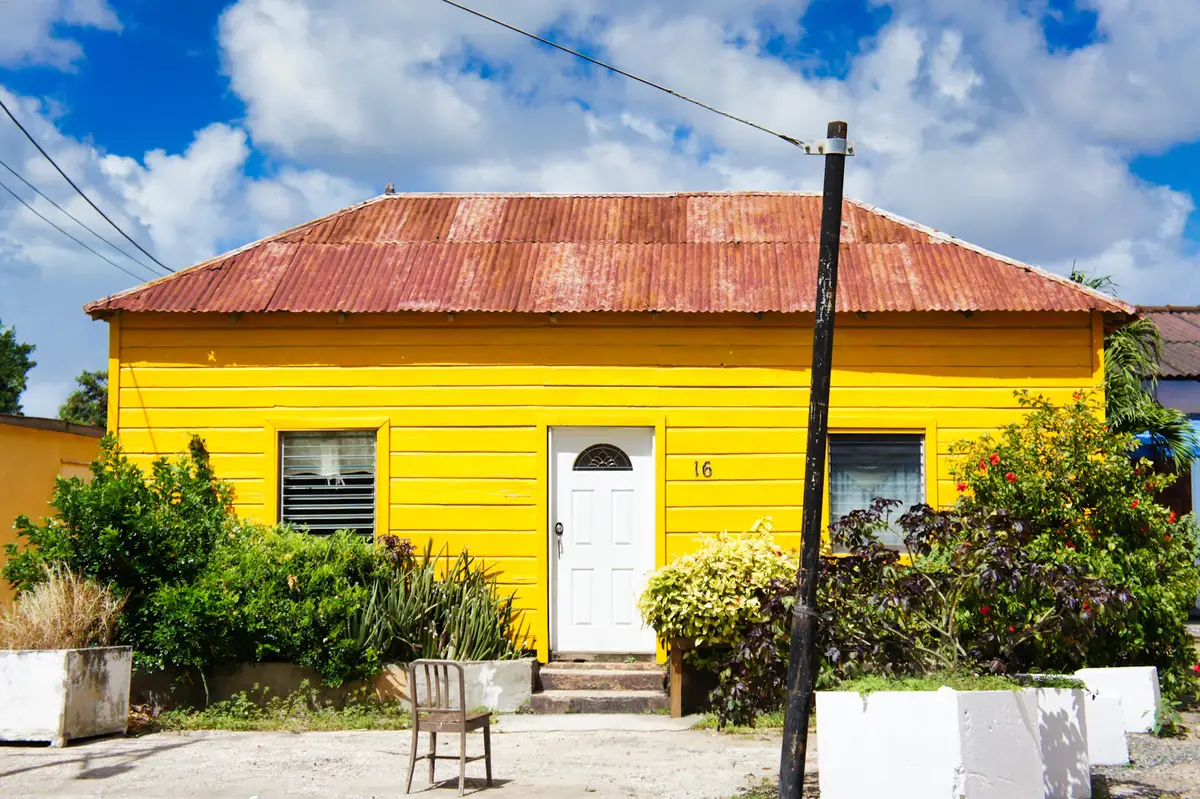 Casa de una planta con fachada pintada de amarillo y techo de zinc.