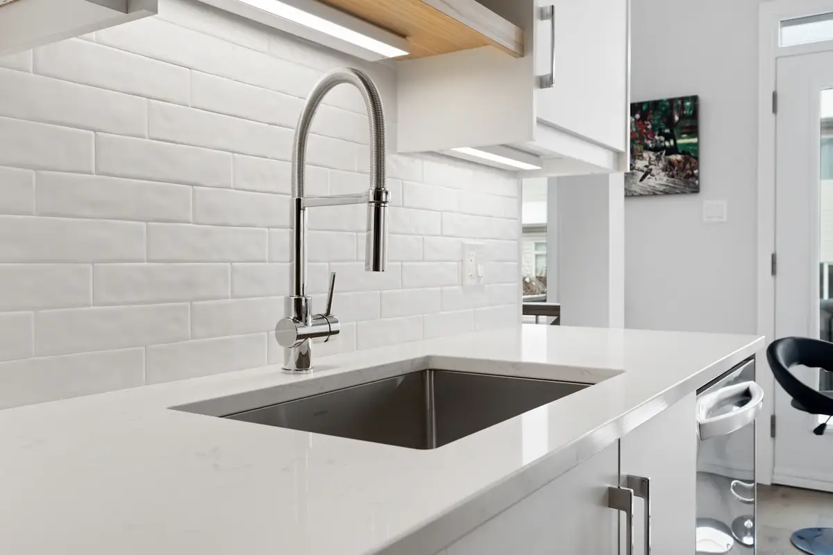 Fregadero de acero con llave nueva sobre un tope blanco de cocina.
